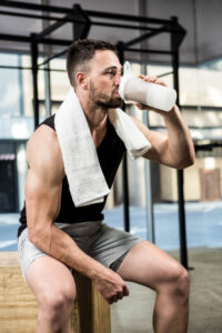 muscular-man-drinking-protein-shake-crossfit-gym